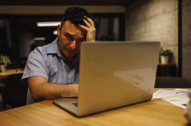 Homme en perte de confiance chez les dirigeants, se tenant la tête devant son ordinateur, illustrant le besoin d’un accompagnement par le mentorat.